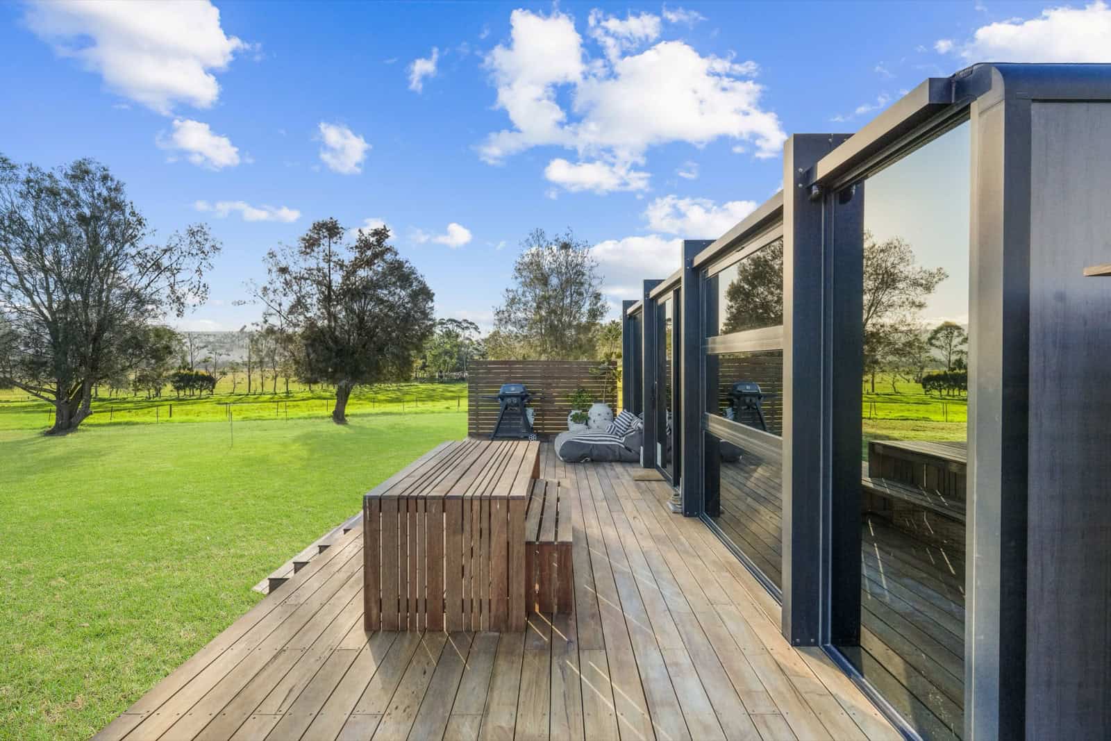 The long timber deck of the Berry pod with hardwood dining bench looking out over farmland