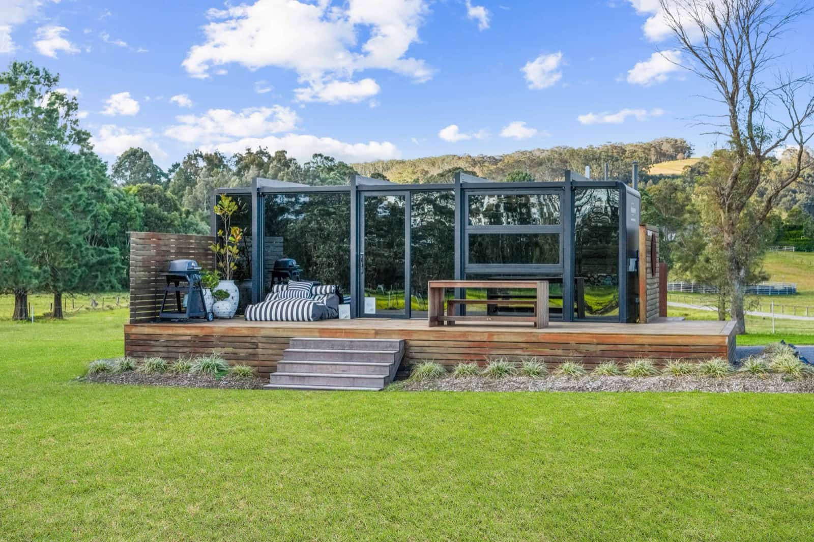 Elsewhere Pods 8m tiny home on a timber deck in a green paddock at Berry, New South Wales