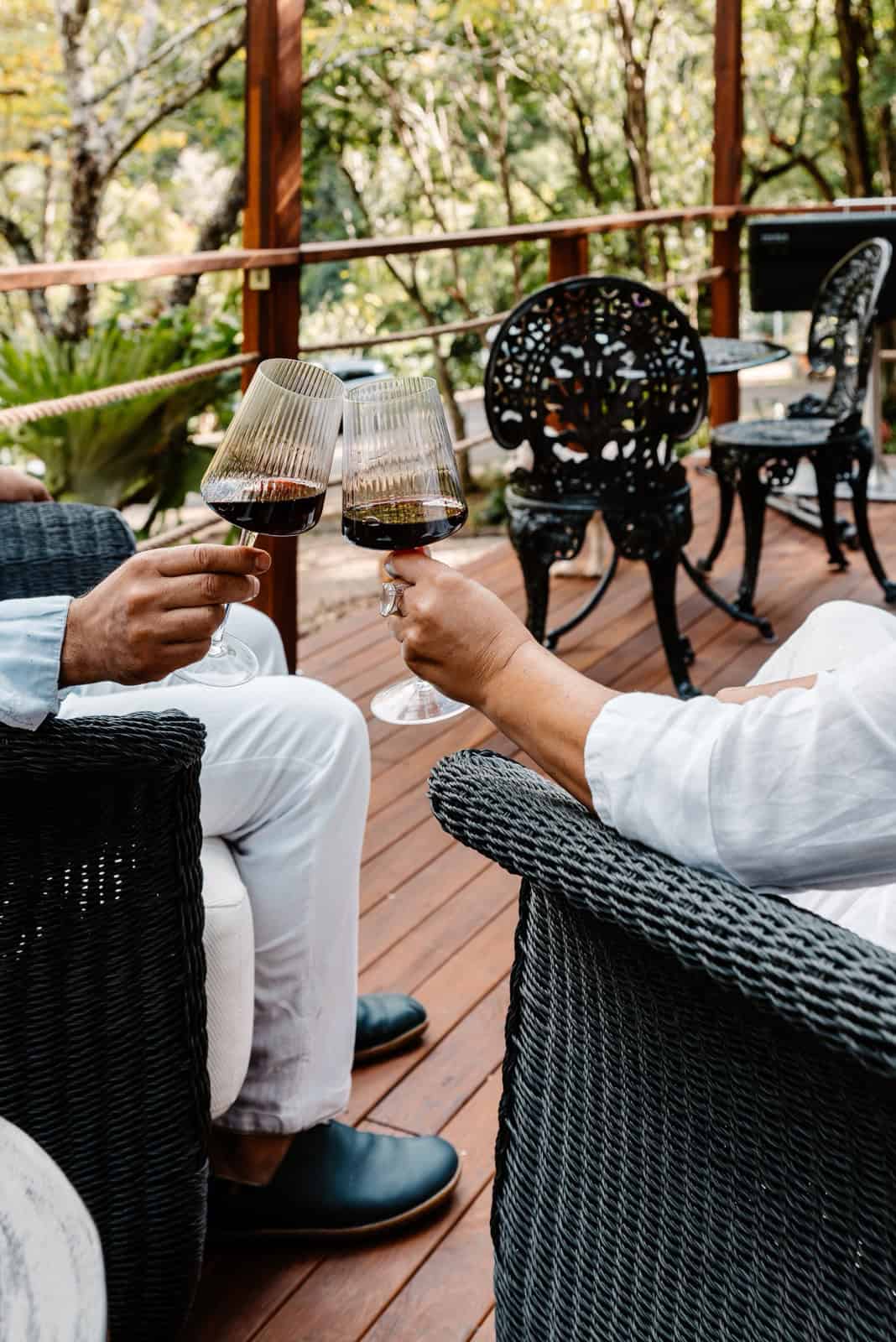 Guests relaxing with wine on the covered deck of the Peachester pod, surrounded by rainforest