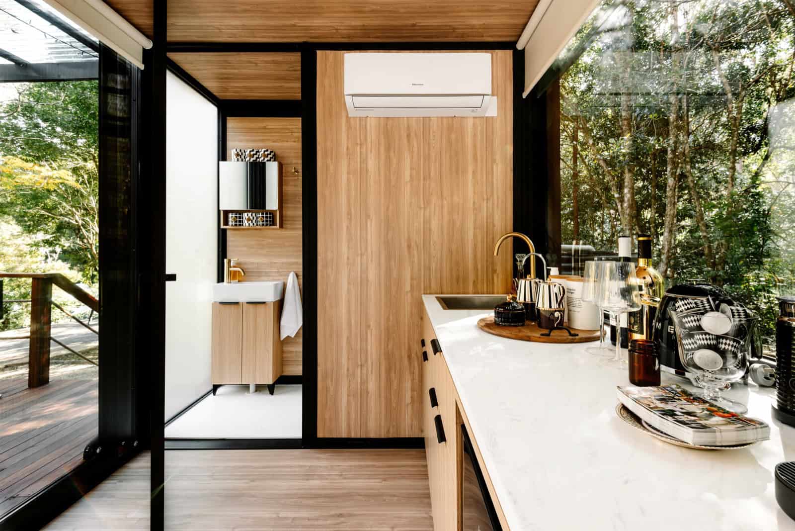 Kitchenette with marble-look benchtop and brass tapware, with the frosted-glass ensuite beyond