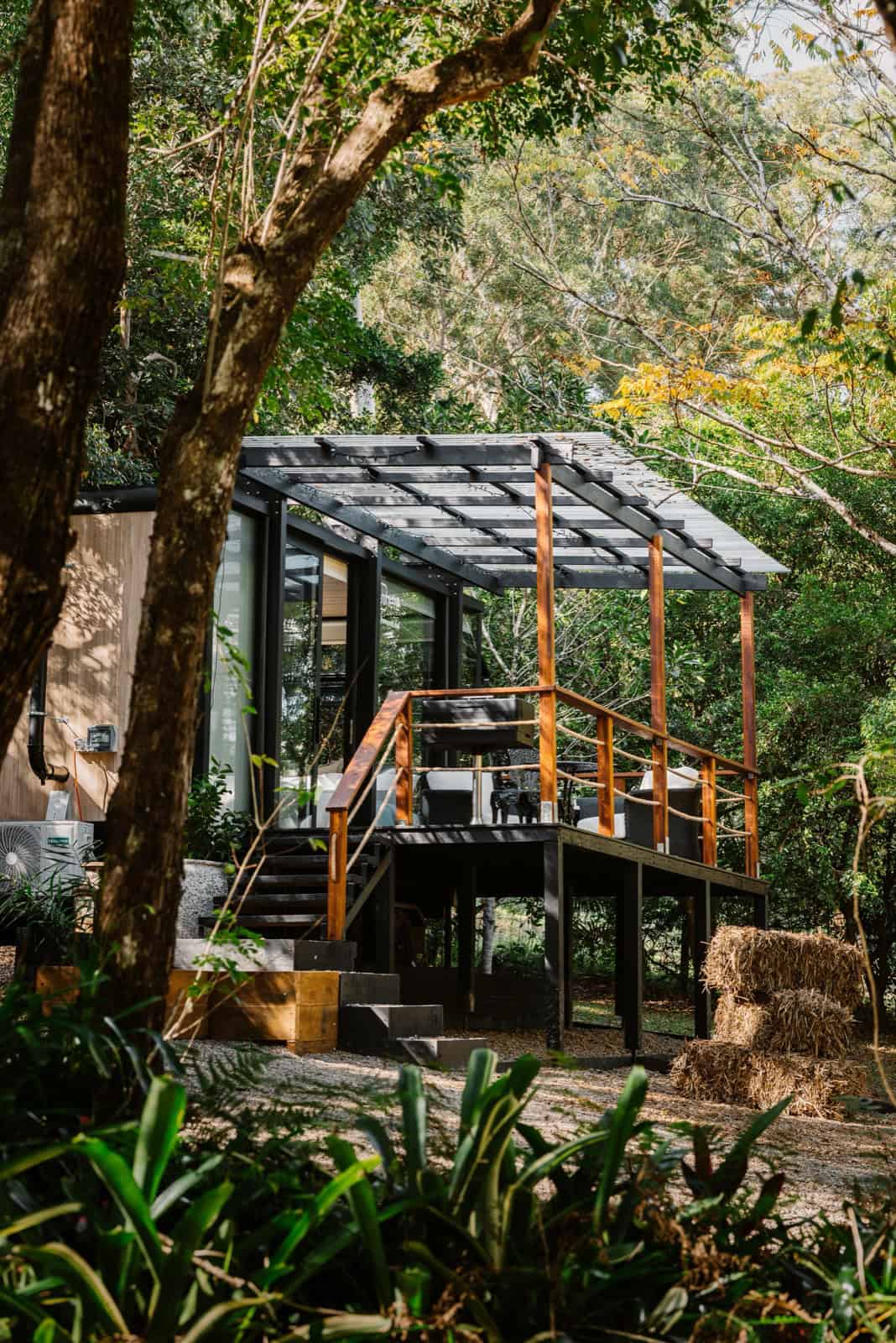 Exterior of the Peachester pod raised on a steel-post deck platform with a polycarbonate-roofed pergola