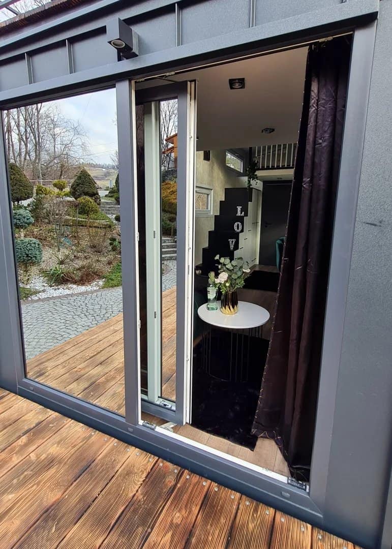A dark torched-wood build of the Erica tiny house with a spiral staircase to a rooftop terrace