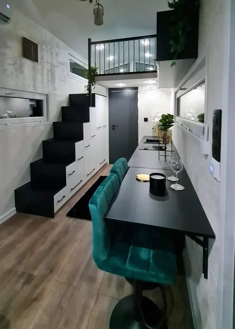 Black dining bar with a green velvet stool beside the storage staircase in the dark Erica build