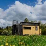 The Erica tiny house by Craft House in yellow and black with a rooftop terrace, set in a Polish meadow