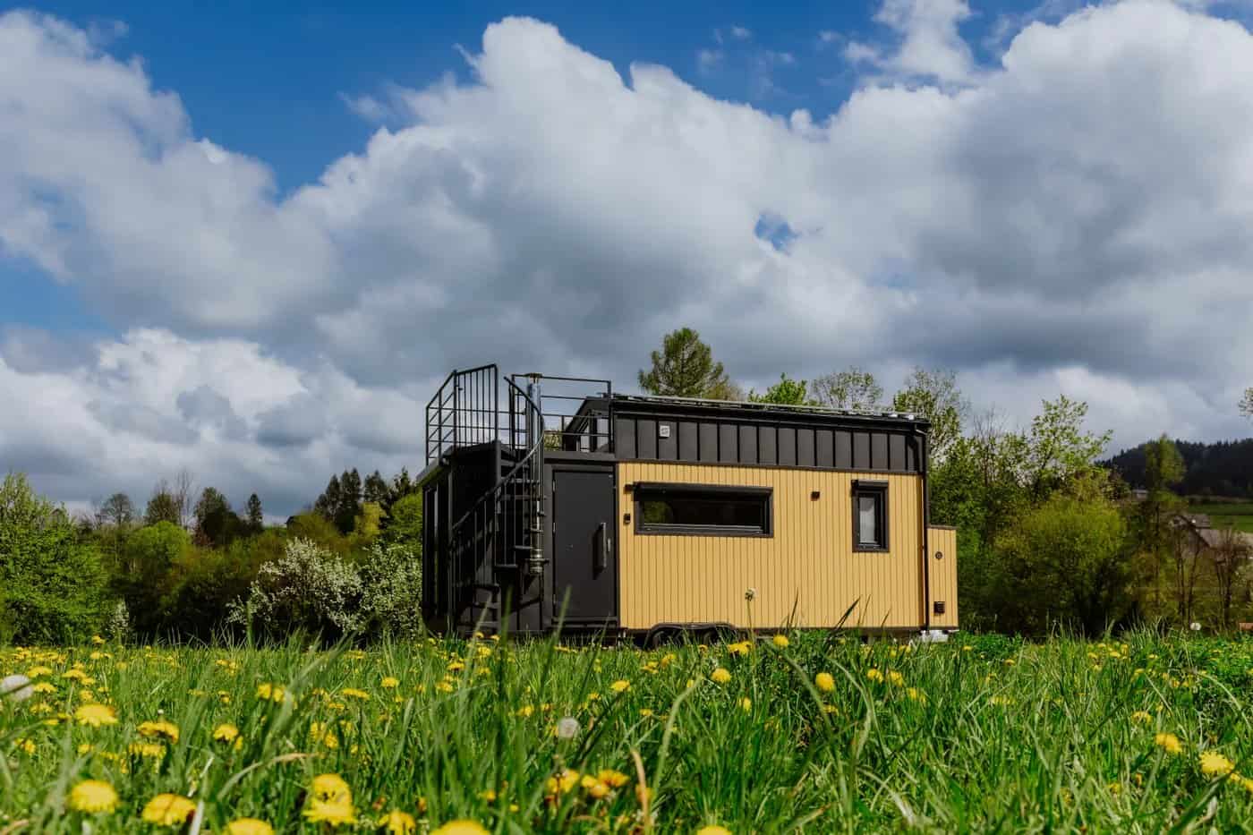 The Erica tiny house by Craft House in yellow and black with a rooftop terrace, set in a Polish meadow