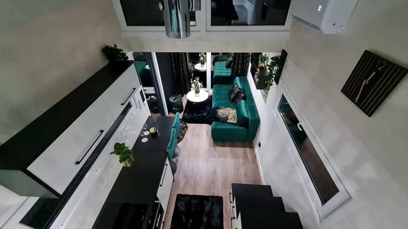 View down to the living area of the dark Erica build with a green velvet sofa