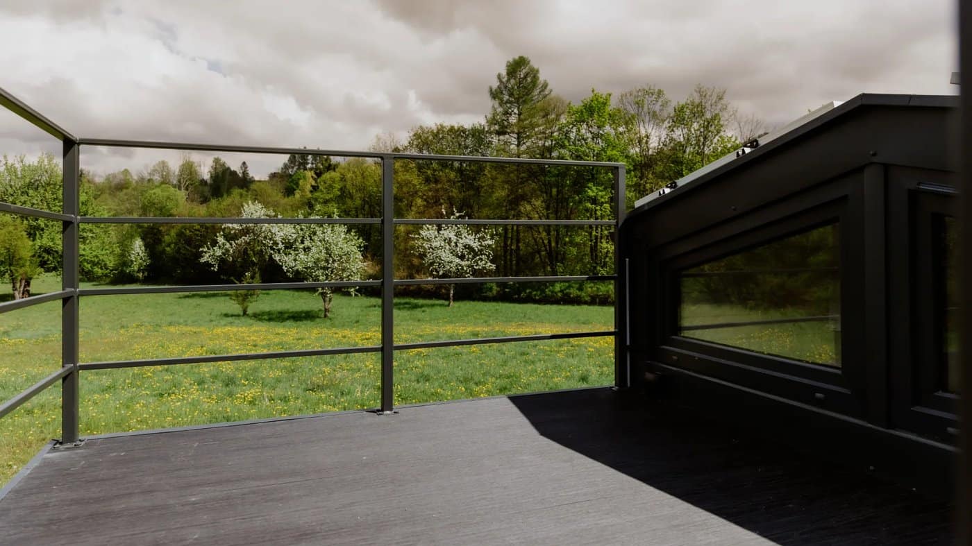 The rooftop terrace deck of the Erica with a metal railing and meadow views