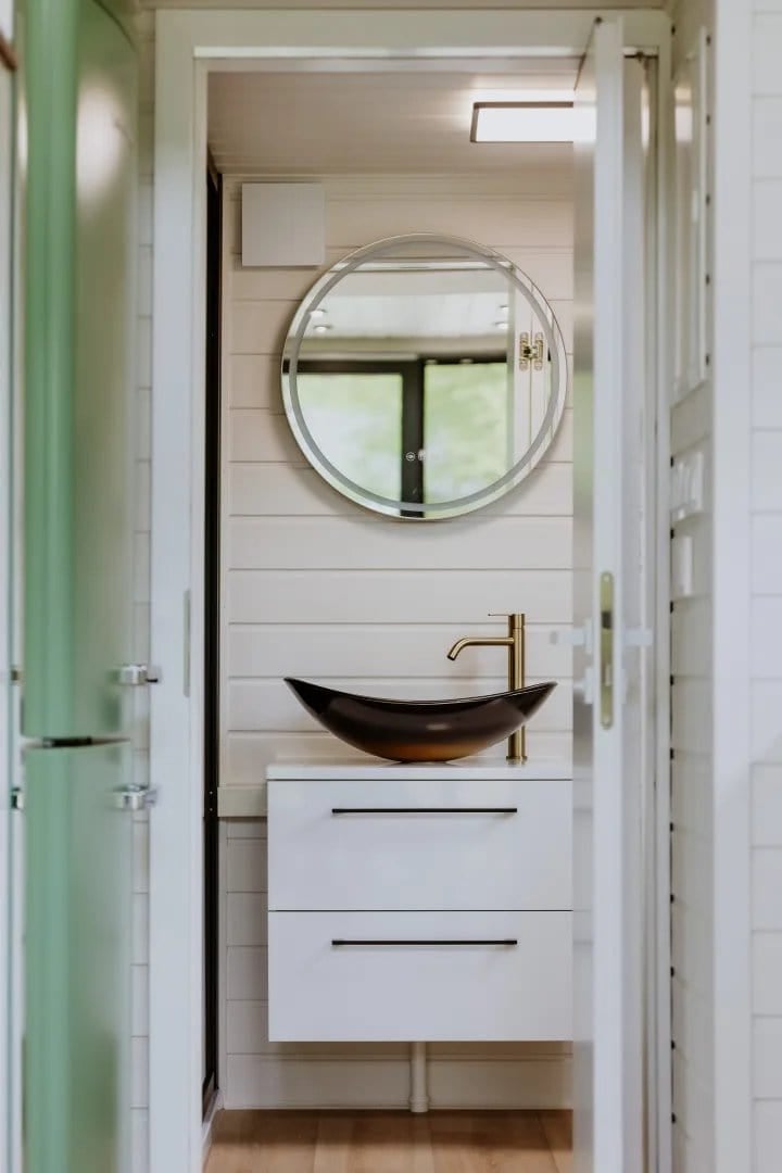 Bathroom in the Scandinavian Erica build with a round LED mirror and a black vessel sink