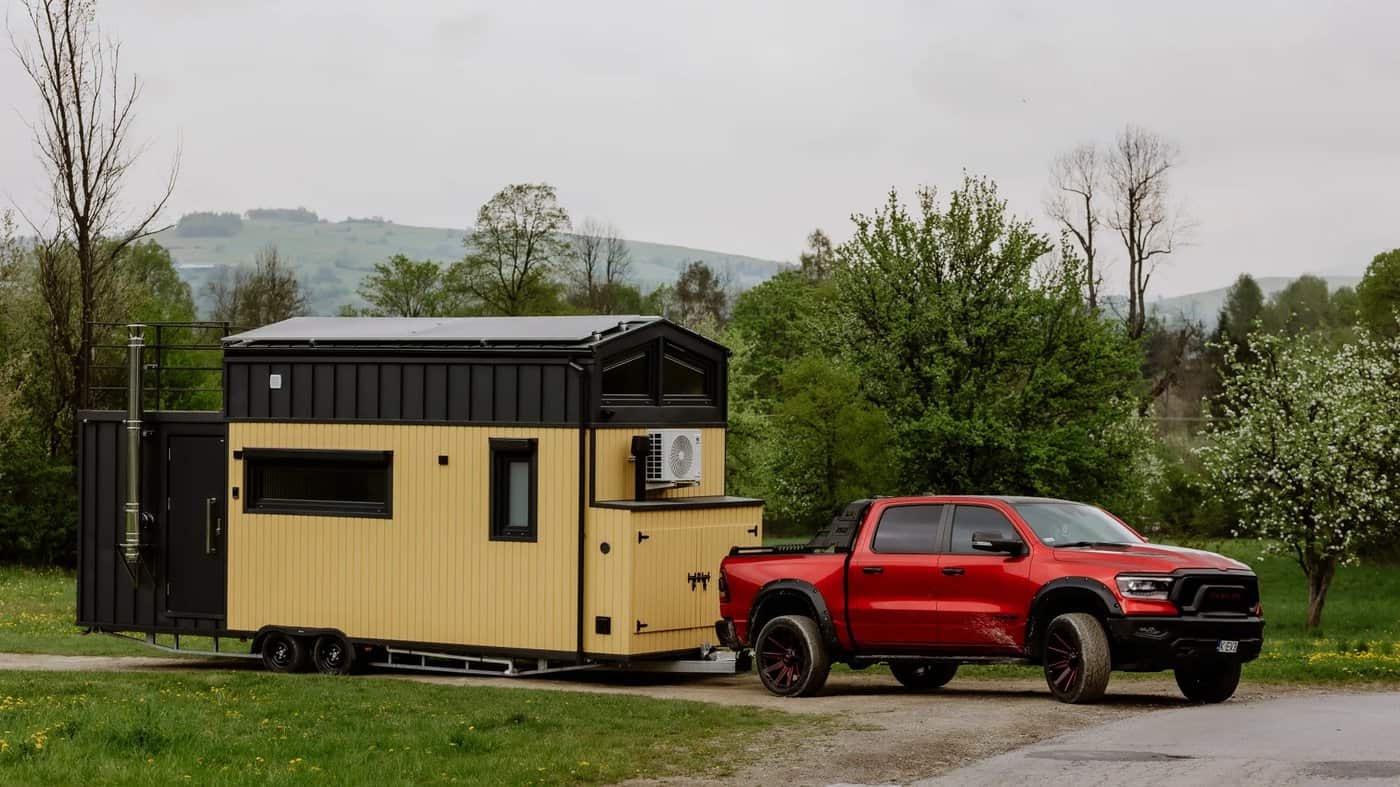 The Erica tiny house being towed down a country road by a pickup truck