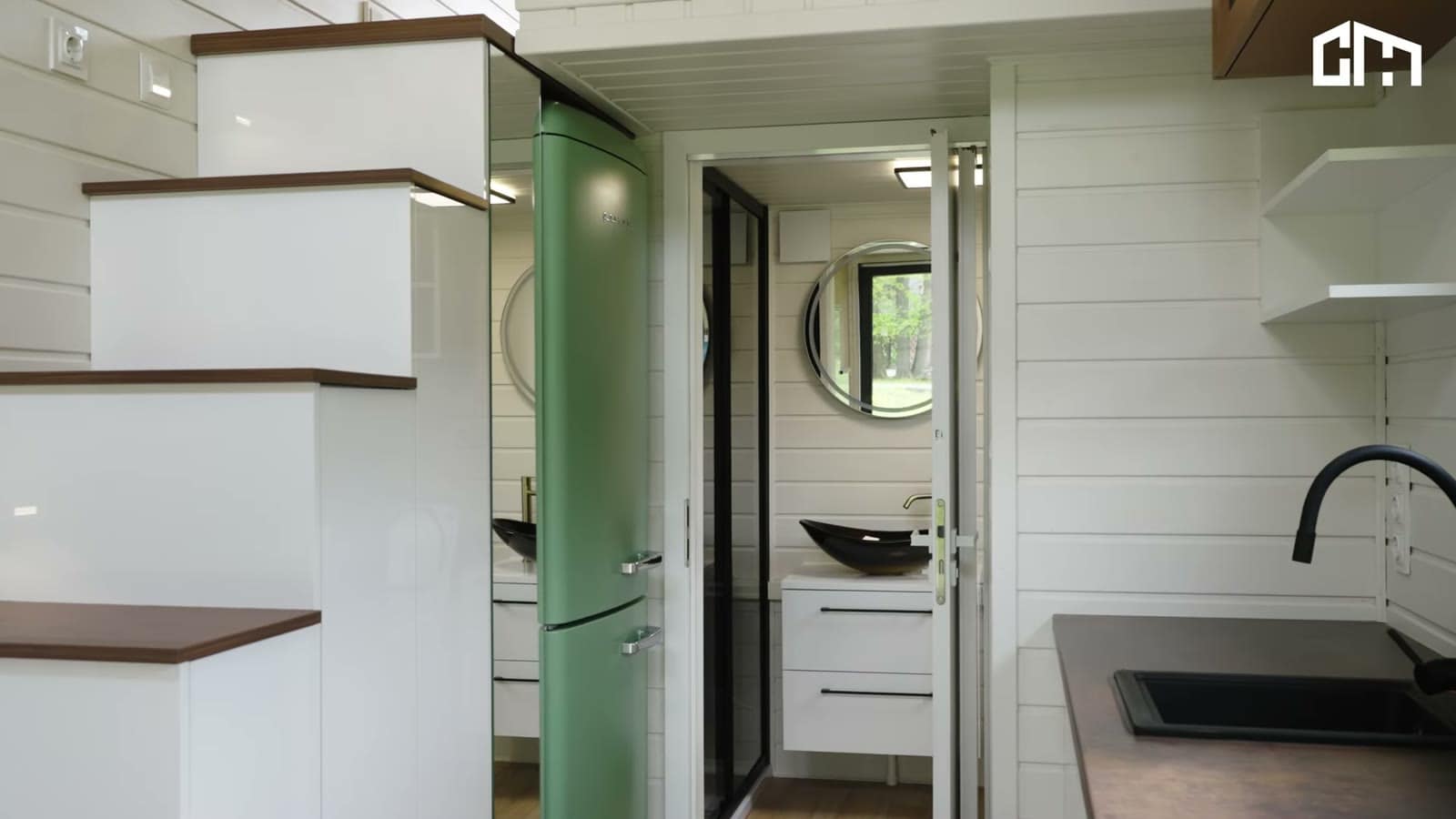 White storage staircase with wood treads beside a green retro refrigerator and the open bathroom door