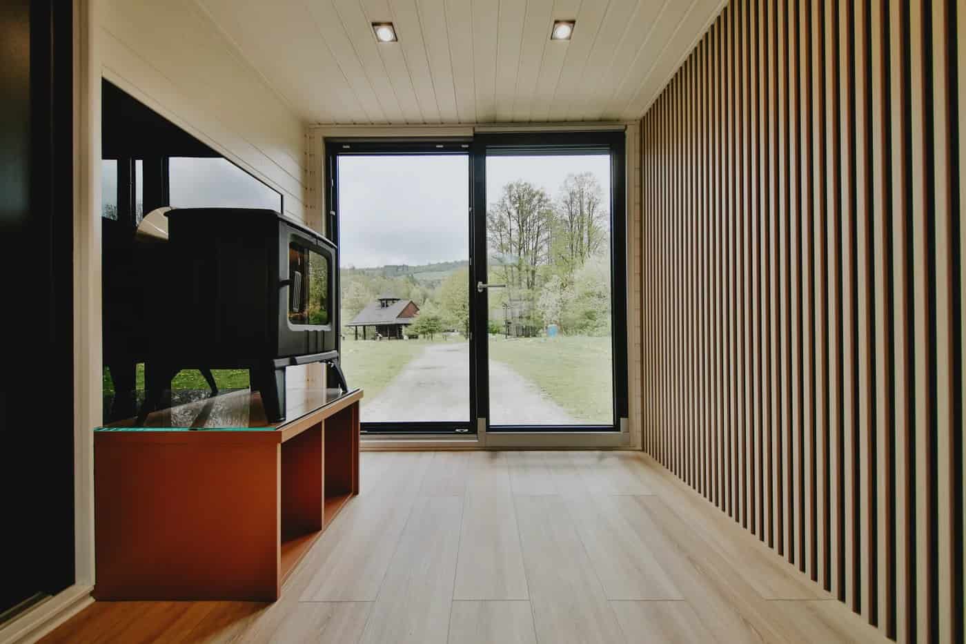 Living area of the Scandinavian Erica build with a black wood-burning stove and floor-to-ceiling glass