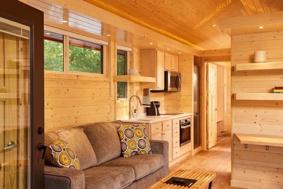 Compact tiny house interior featuring a small kitchen and living area with natural wood accents.