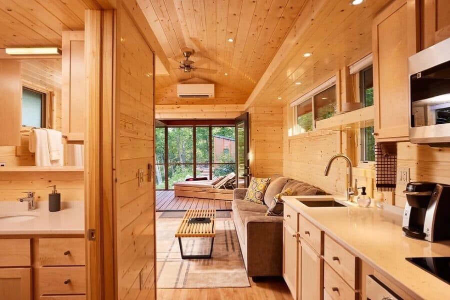 Bright and inviting tiny house interior featuring a compact kitchen, cozy living space, and large wi.