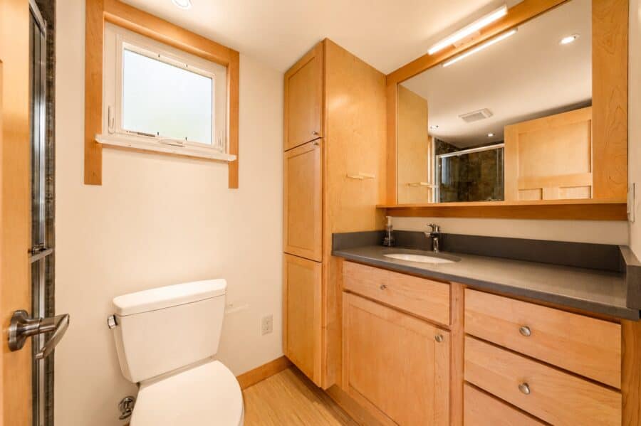 Bathroom in the Traveler XLS Wide with a stone vanity, large mirror, toilet, and window for natural light.