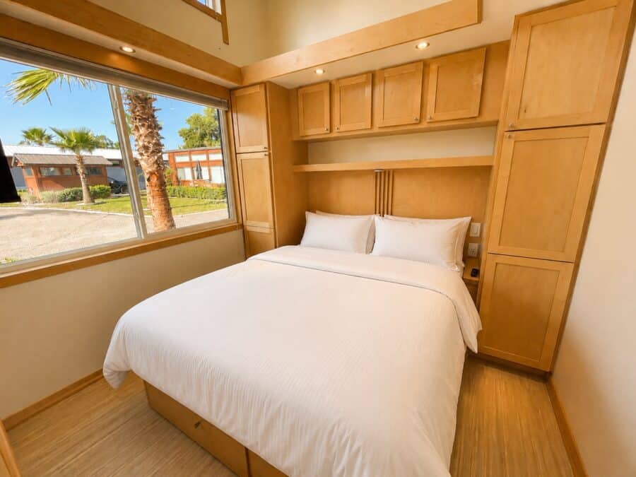 First-floor walk-around Queen bedroom in the ESCAPE Traveler XLS Wide with maple built-in cabinets, double closets, and a large window.