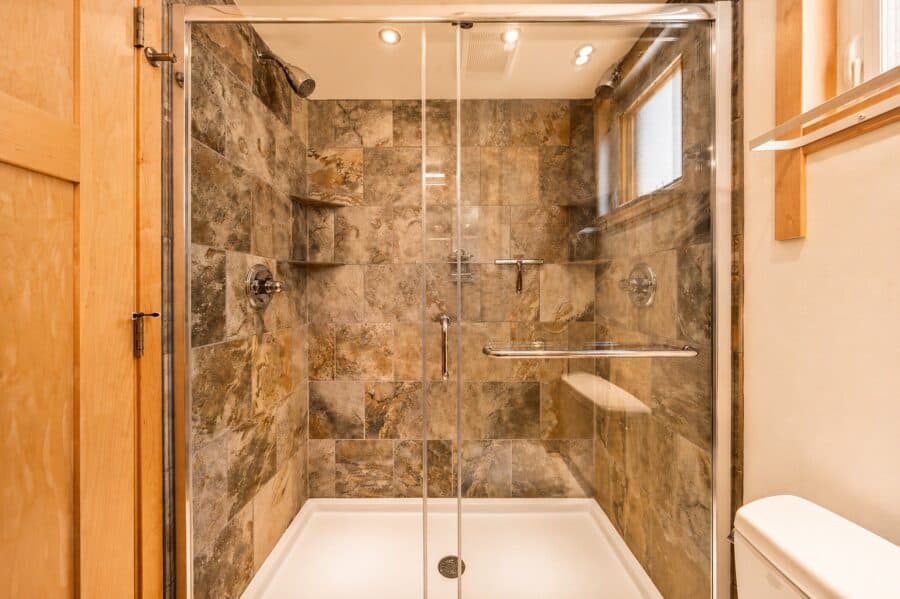 Walk-in tile shower with a glass door and stone tile in the oversized bathroom of the Traveler XLS Wide.