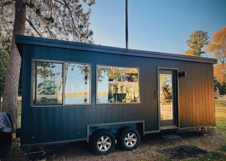 Compact tiny house with large windows and sleek black exterior.