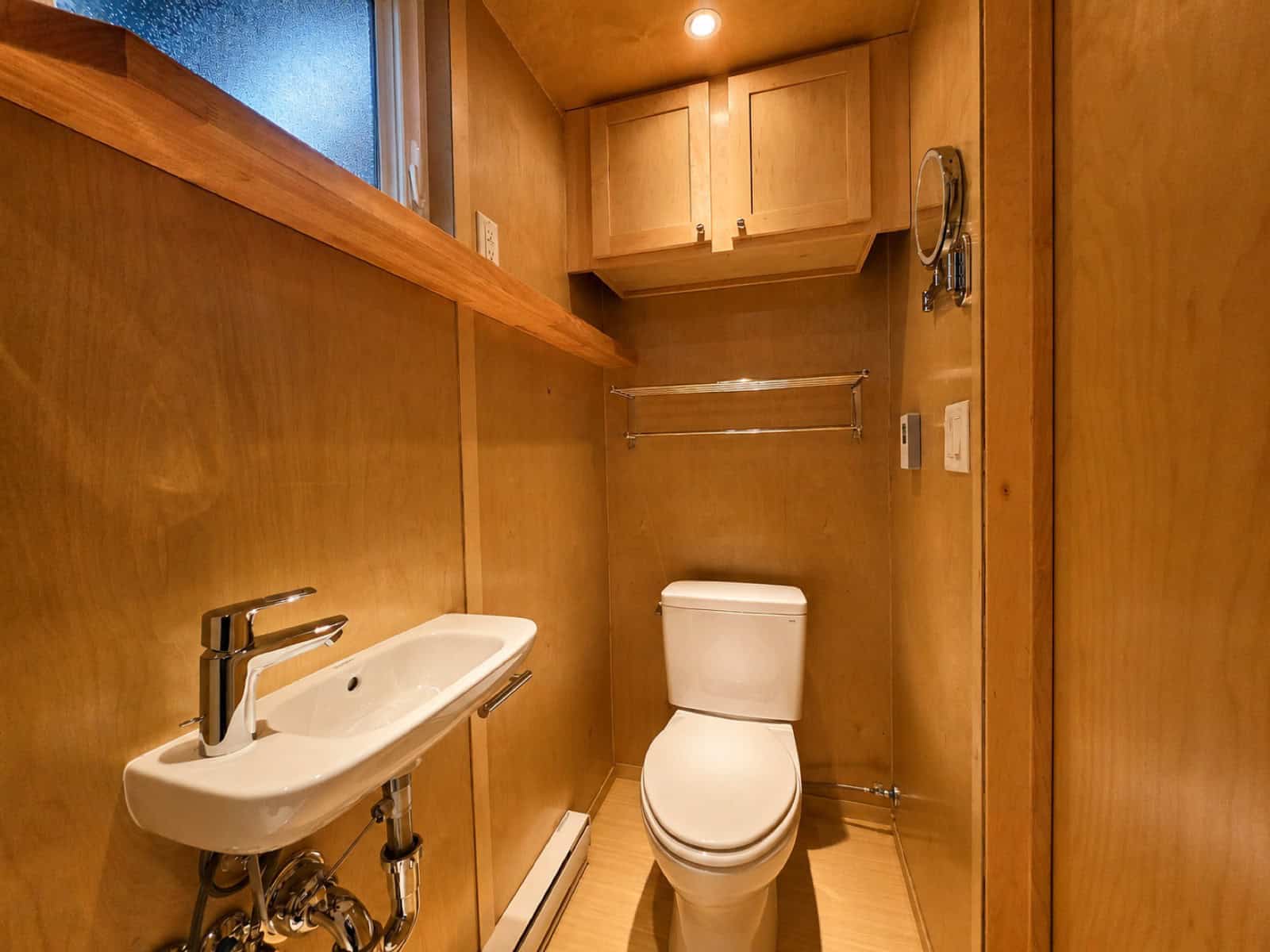 Bathroom in the Escape eBoho GO with wall-hung sink, overhead cabinet and privacy window
