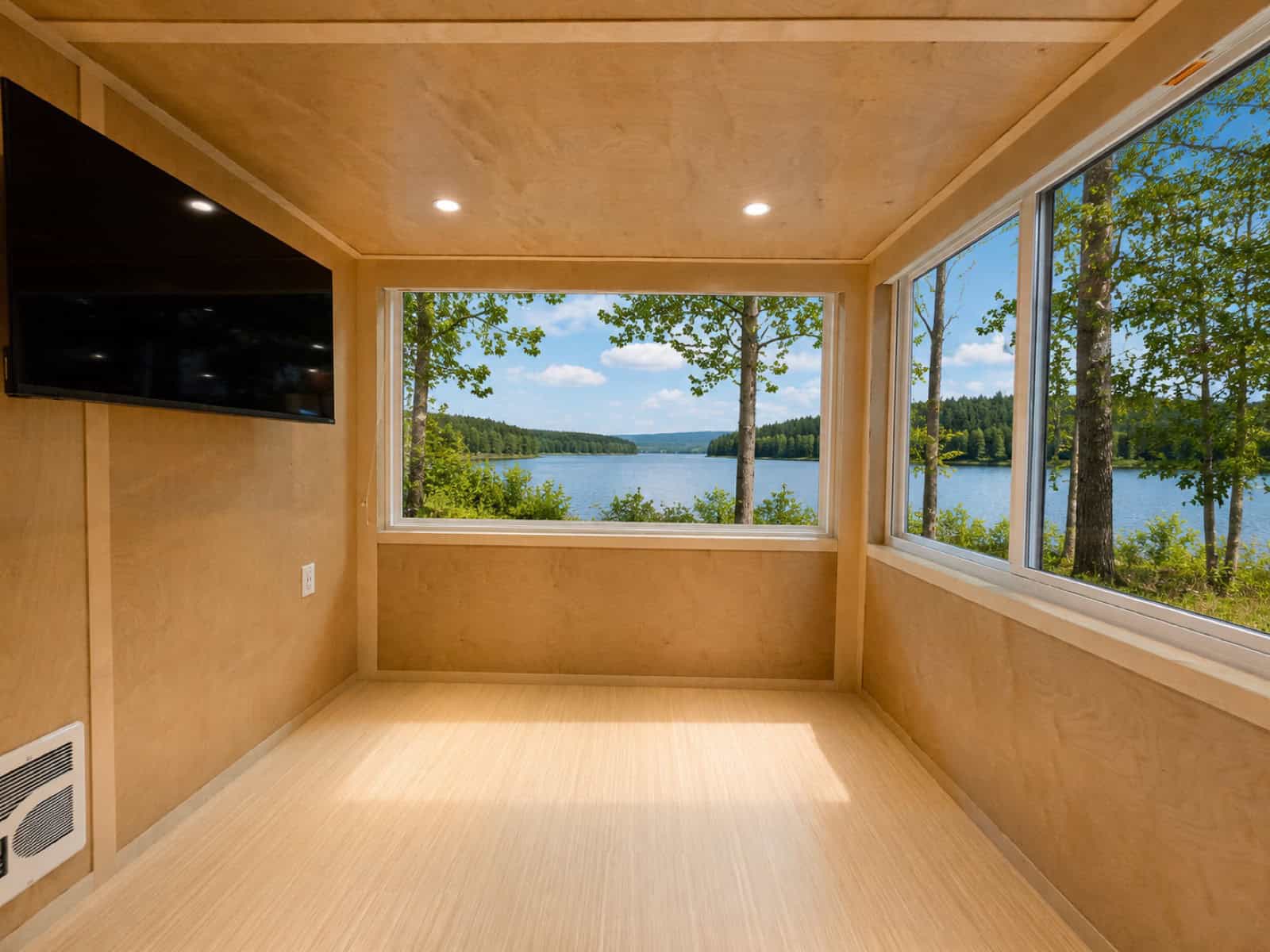 Living area of the Escape eONE Limited Edition with a wall-mounted Smart TV and corner windows