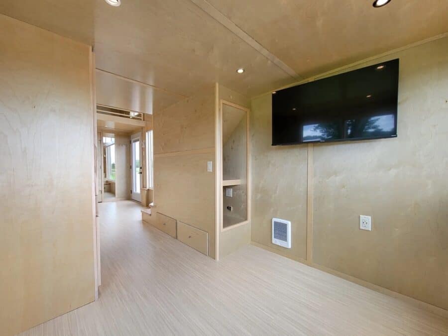 Modern tiny house interior with sleek walls and a large TV for cozy living.