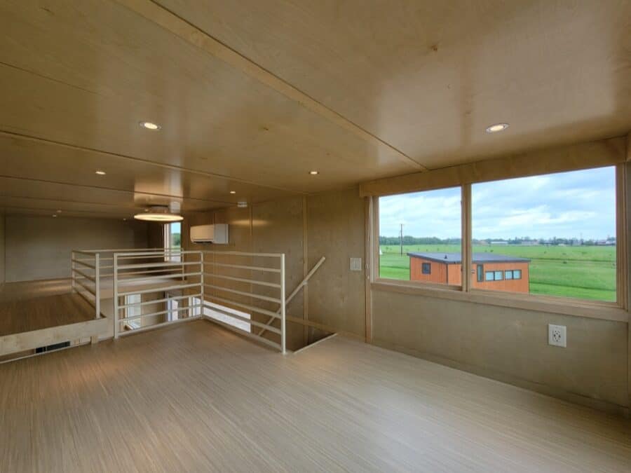 Bright interior of a tiny house with wooden walls and flooring, showcasing a spacious area and sceni.