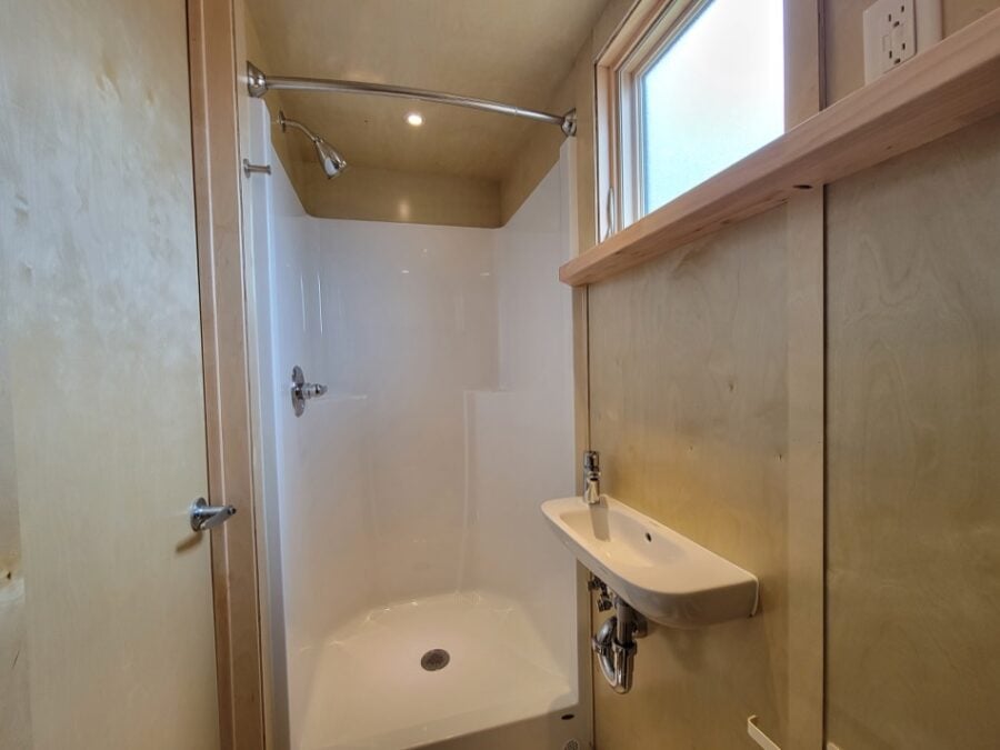 Compact tiny house bathroom with a shower and small sink.