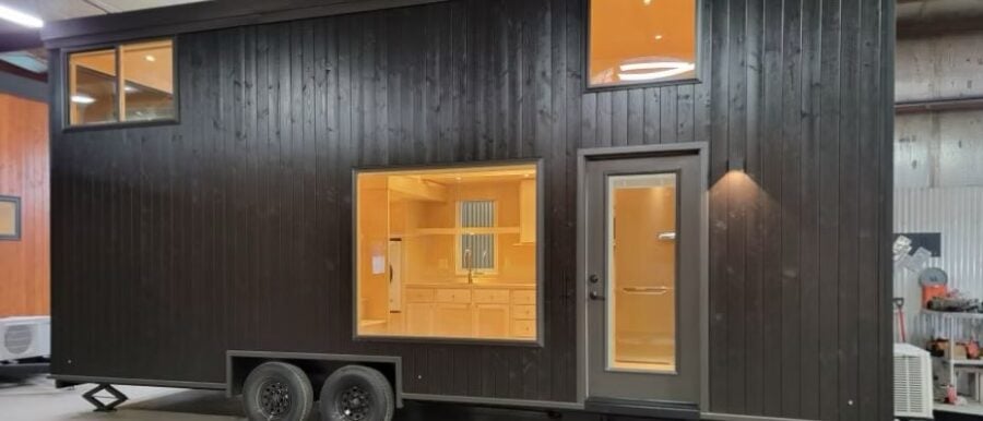 Compact tiny house on wheels with modern black exterior and large window. Perfect for small space li.