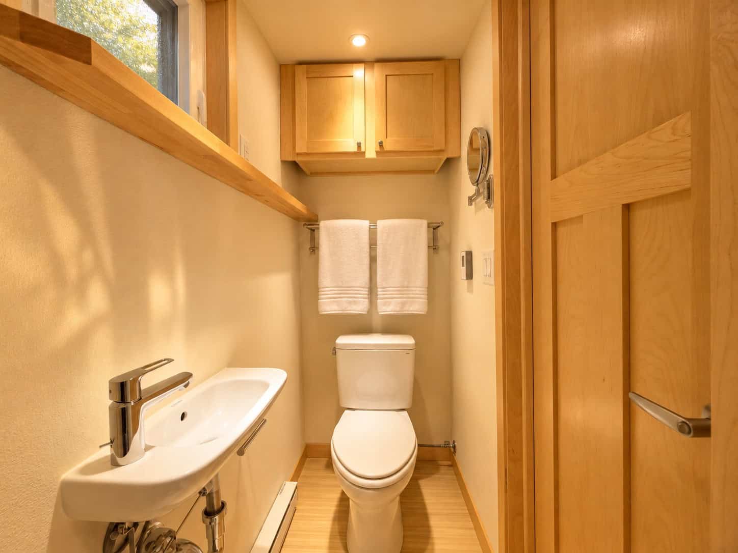 Bathroom in the eVista XL Limited with toilet, wall-mounted sink, and maple upper cabinets