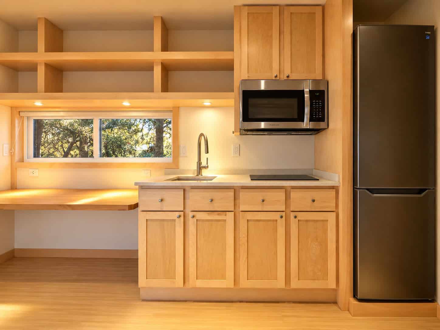 Maple kitchen in the eVista XL Limited with quartz counters, induction cooktop, microwave convection oven, and tall refrigerator