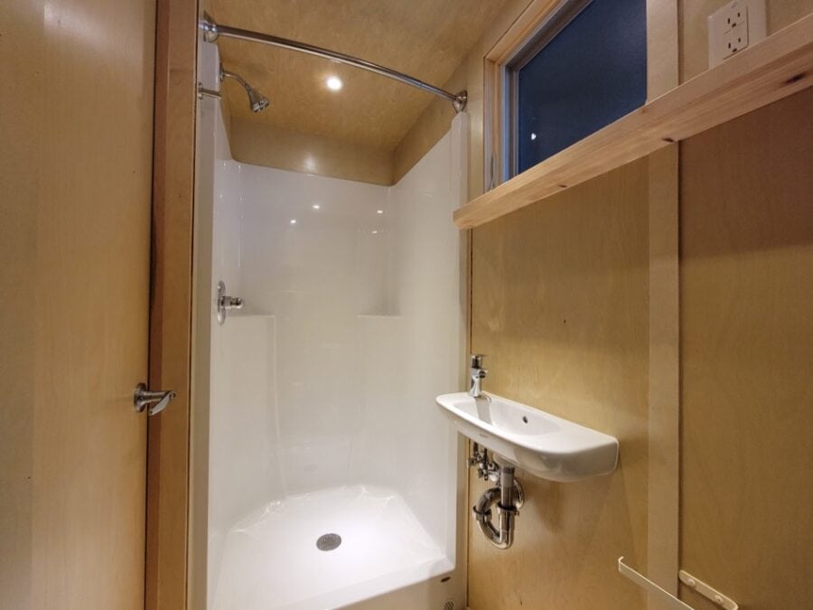 Compact tiny house bathroom with a shower and small sink.