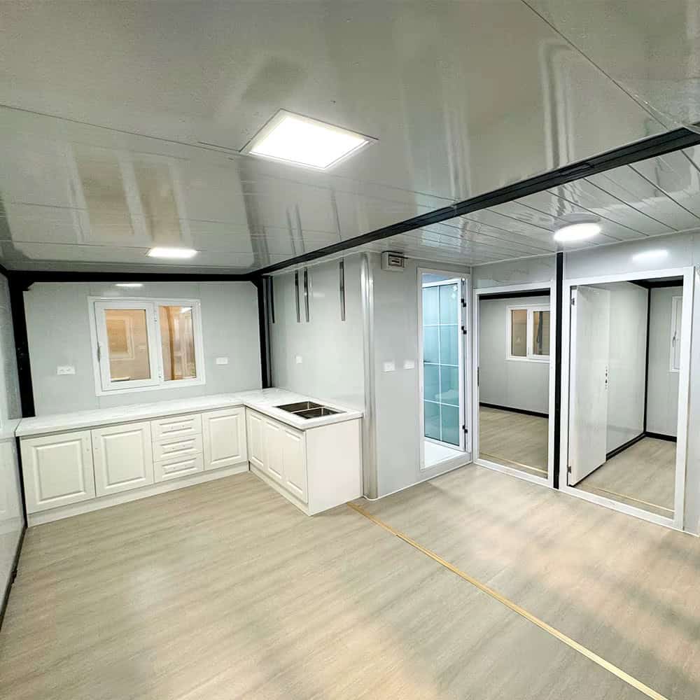 Open floor plan interior showing L-shaped kitchen with white cabinets and doorways to two bedrooms