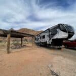 RV parked near a picnic shelter in a desert landscape.