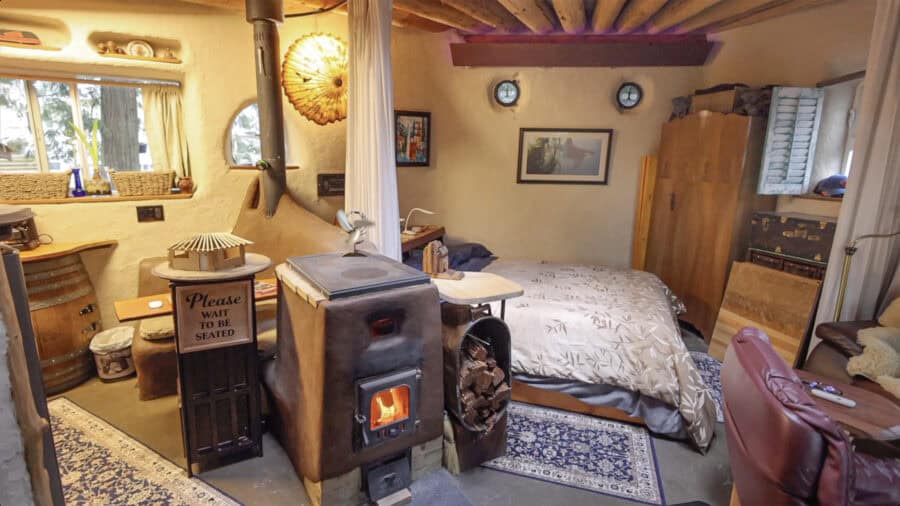 Interior of a wobbly hobbit-style tiny house with warm lighting and rustic decor.