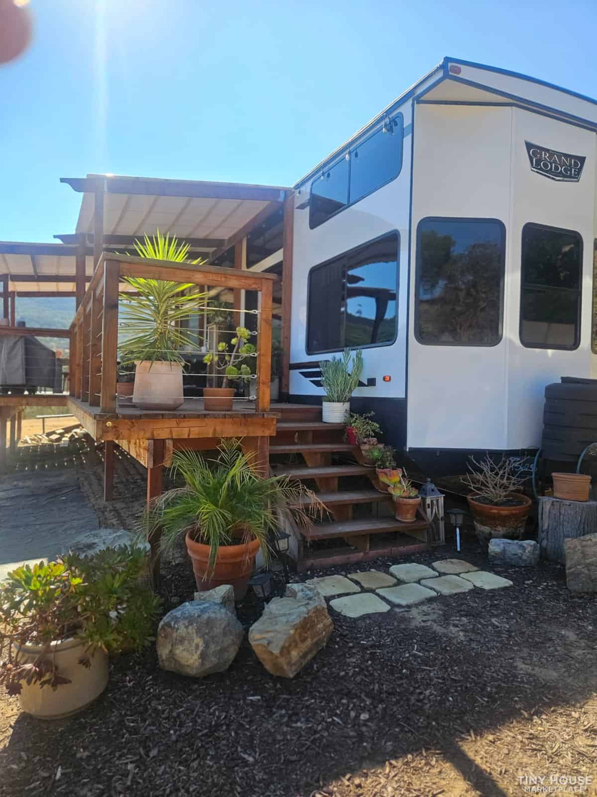 Tiny house with outdoor deck and lush potted plants for small space living.