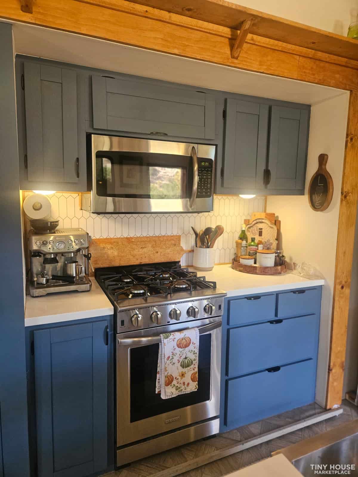 Kitchen detail showing gas range, navy blue shaker cabinets, white hexagonal backsplash, and espresso machine