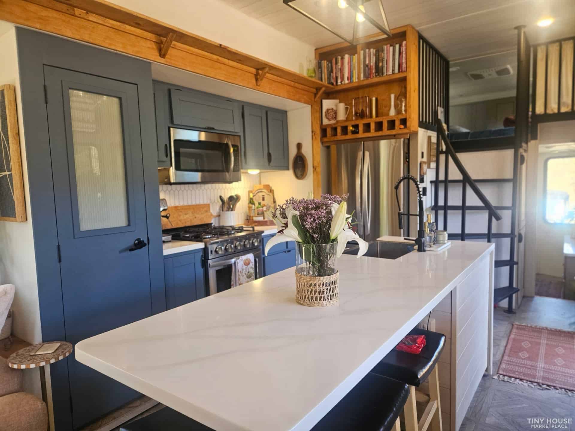 Kitchen with navy blue custom cabinets, white quartz island, stainless steel appliances, and hexagonal backsplash