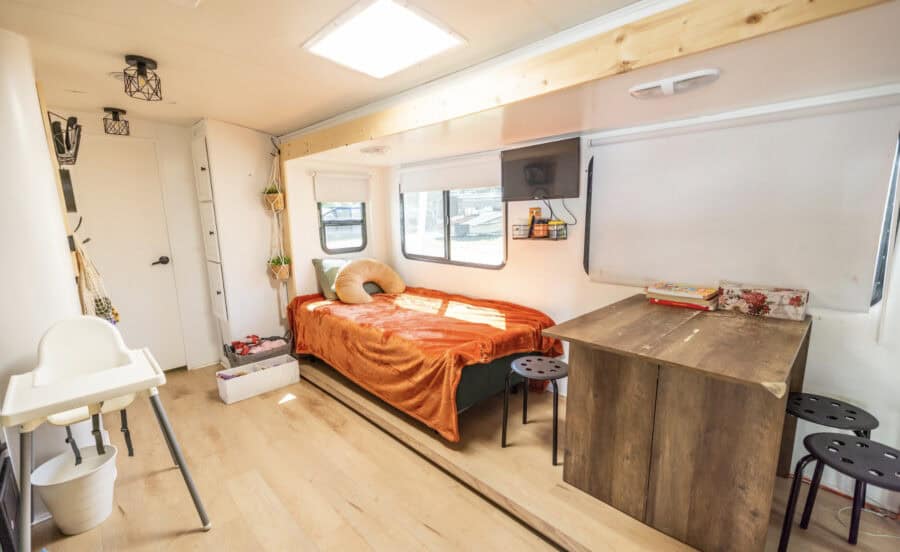 Small living space inside a tiny house with a bed, table, and compact furniture.