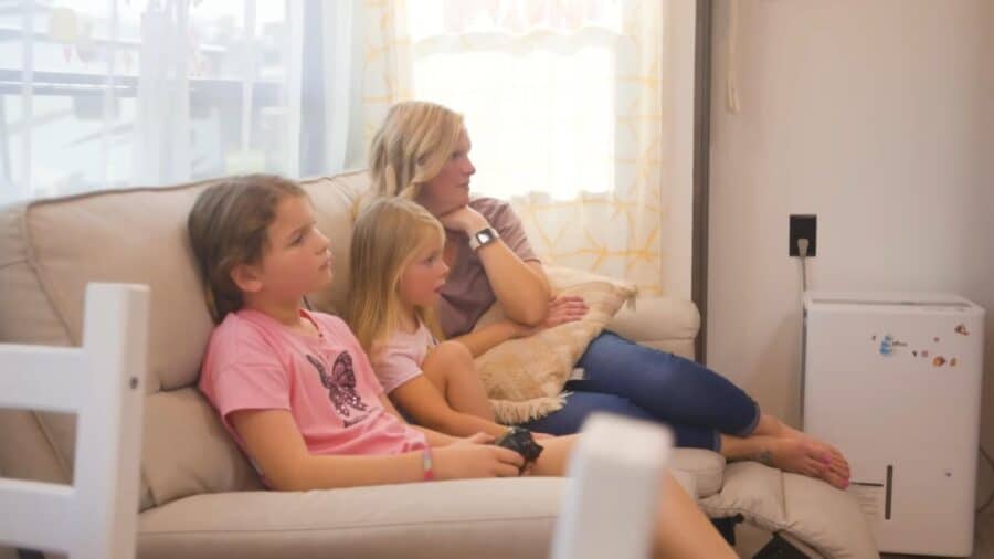 Family relaxing on a cozy sofa in a small living space with natural light.