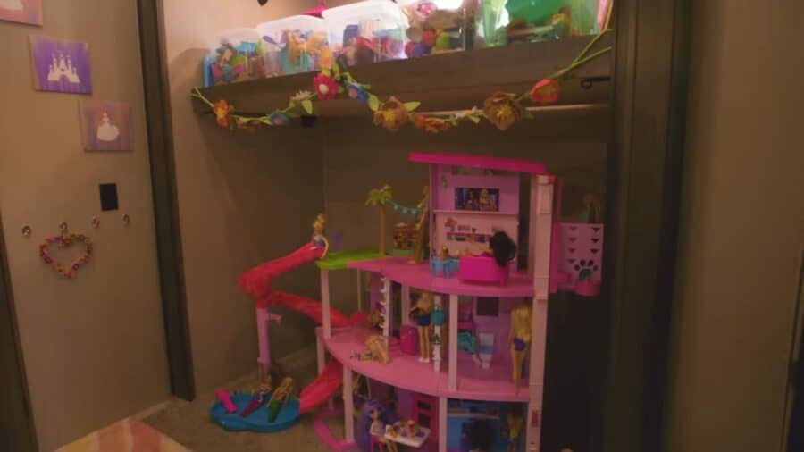 Colorful pink multi-story dollhouse with furniture and accessories for kids.