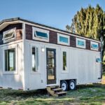 Lofted farmhouse tiny home with multiple windows and modern design by Florida Tiny House Builders.