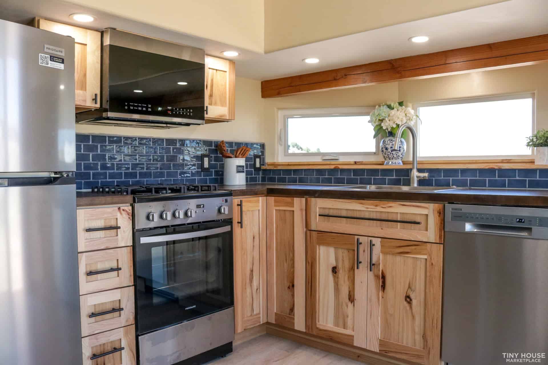 Chef's kitchen with hickory cabinets, gas range, dishwasher and navy subway tile