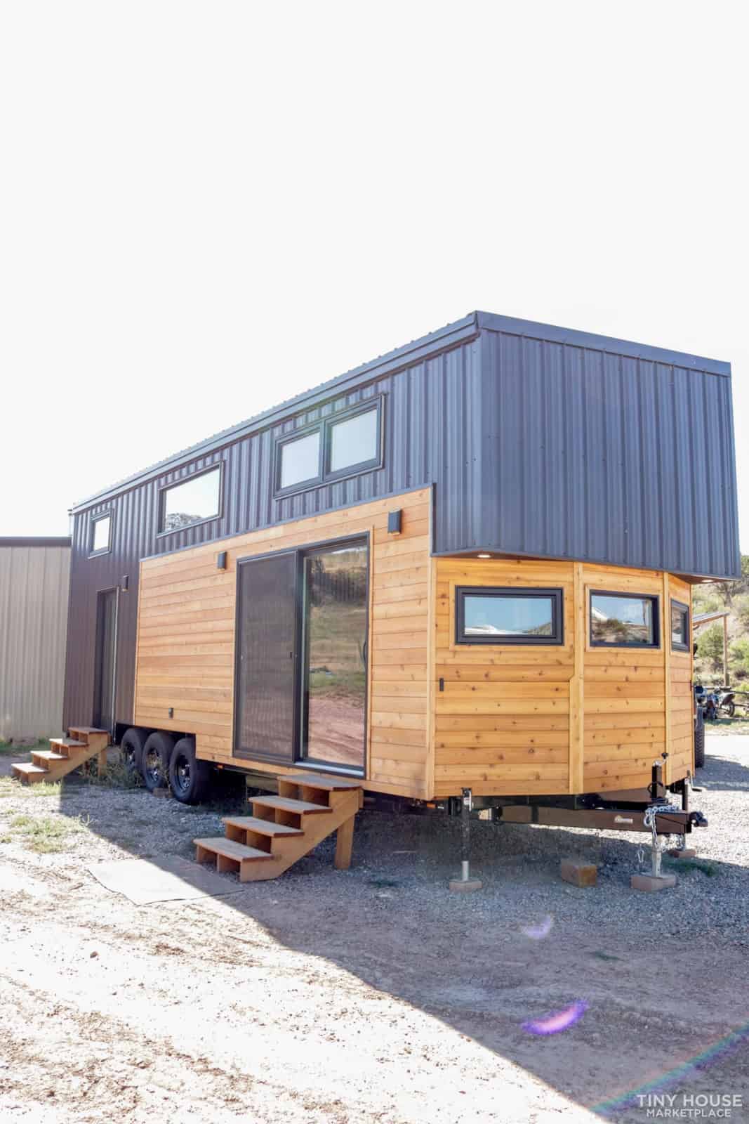 Felicity two-story tiny house on wheels with cedar siding and dark metal cladding