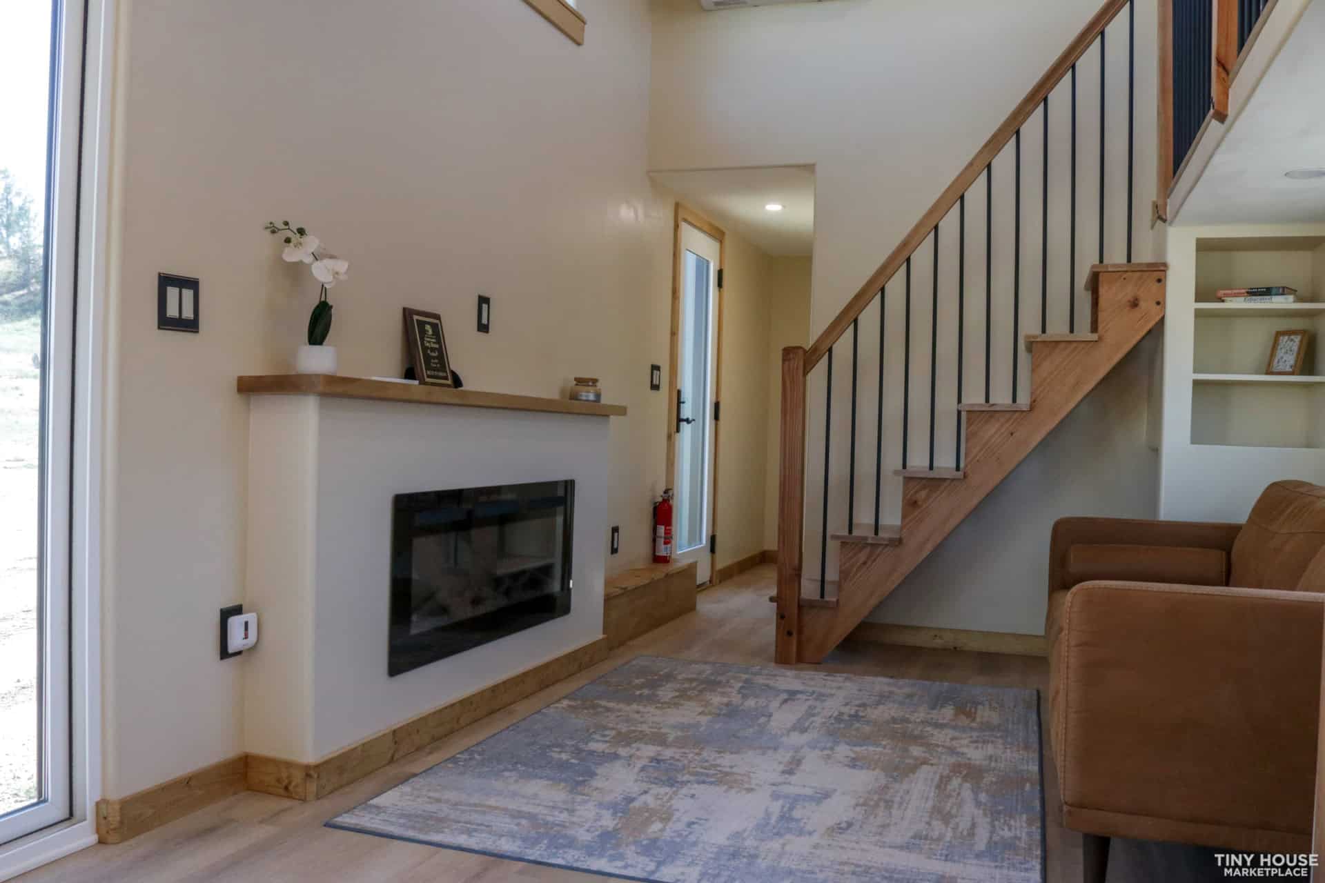 Living room with electric fireplace, mantel and a full staircase to the bedrooms