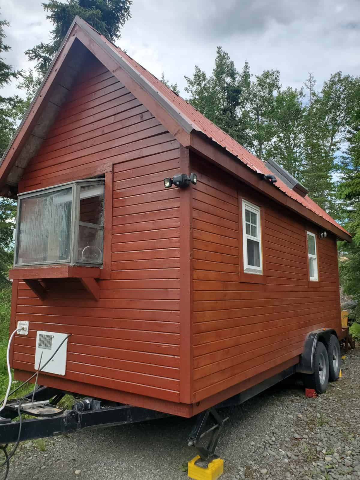 Gable end of the Fencl tiny house showing the projecting bay window, motion lights and skylight