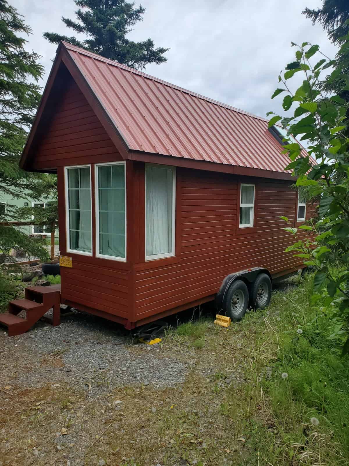 Red cedar-sided Tumbleweed Fencl tiny house on a tandem-axle trailer in Soldotna, Alaska