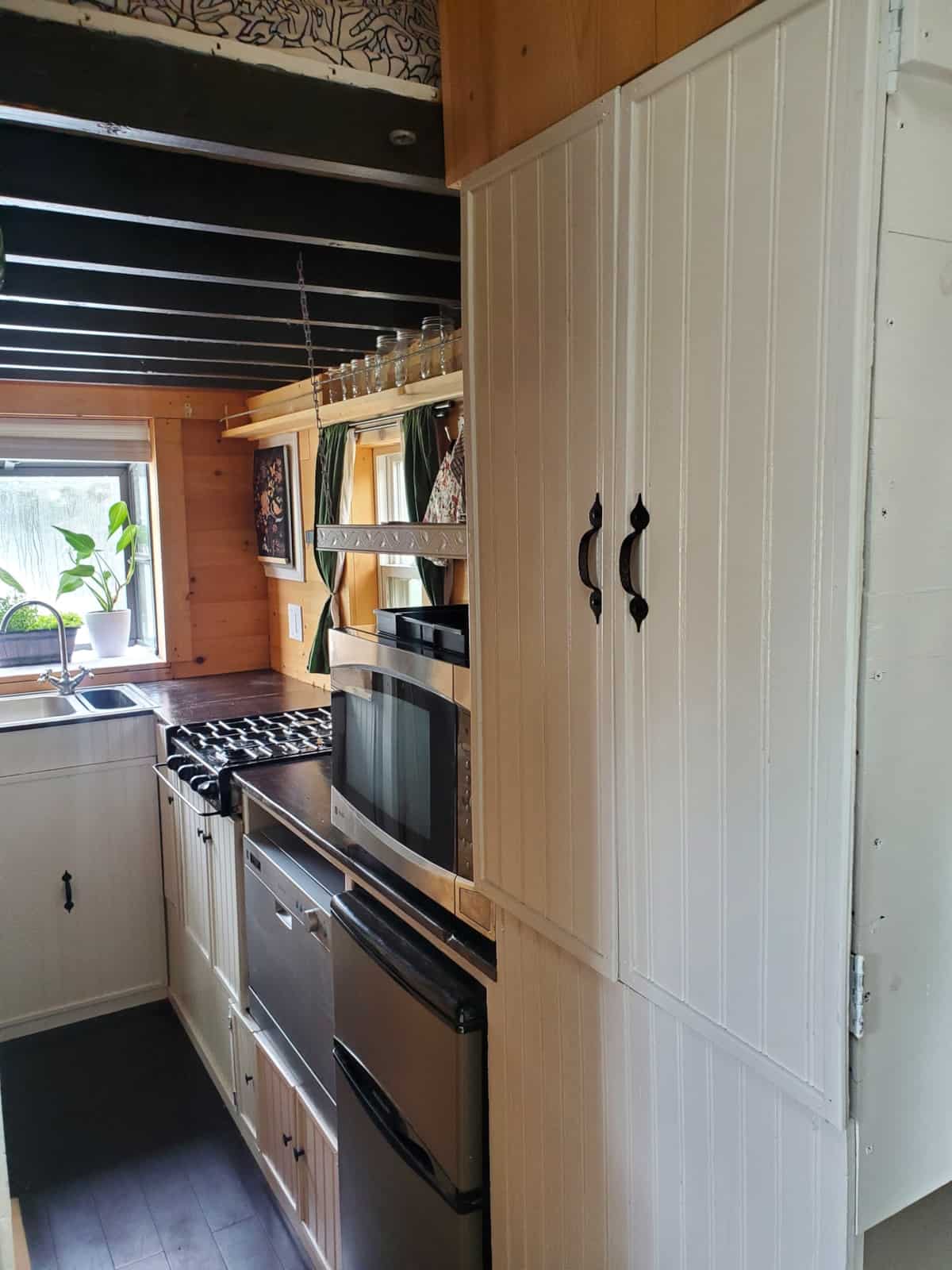 Galley kitchen with propane cooktop, convection microwave, dishwasher, compact fridge and butcher block counter