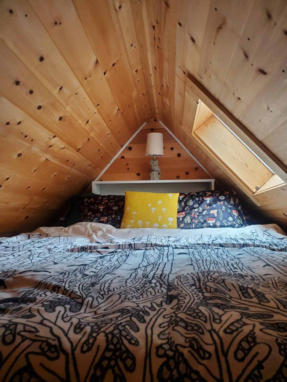 Queen-sized main sleeping loft with pine cathedral ceiling, built-in headboard shelf and opening skylight