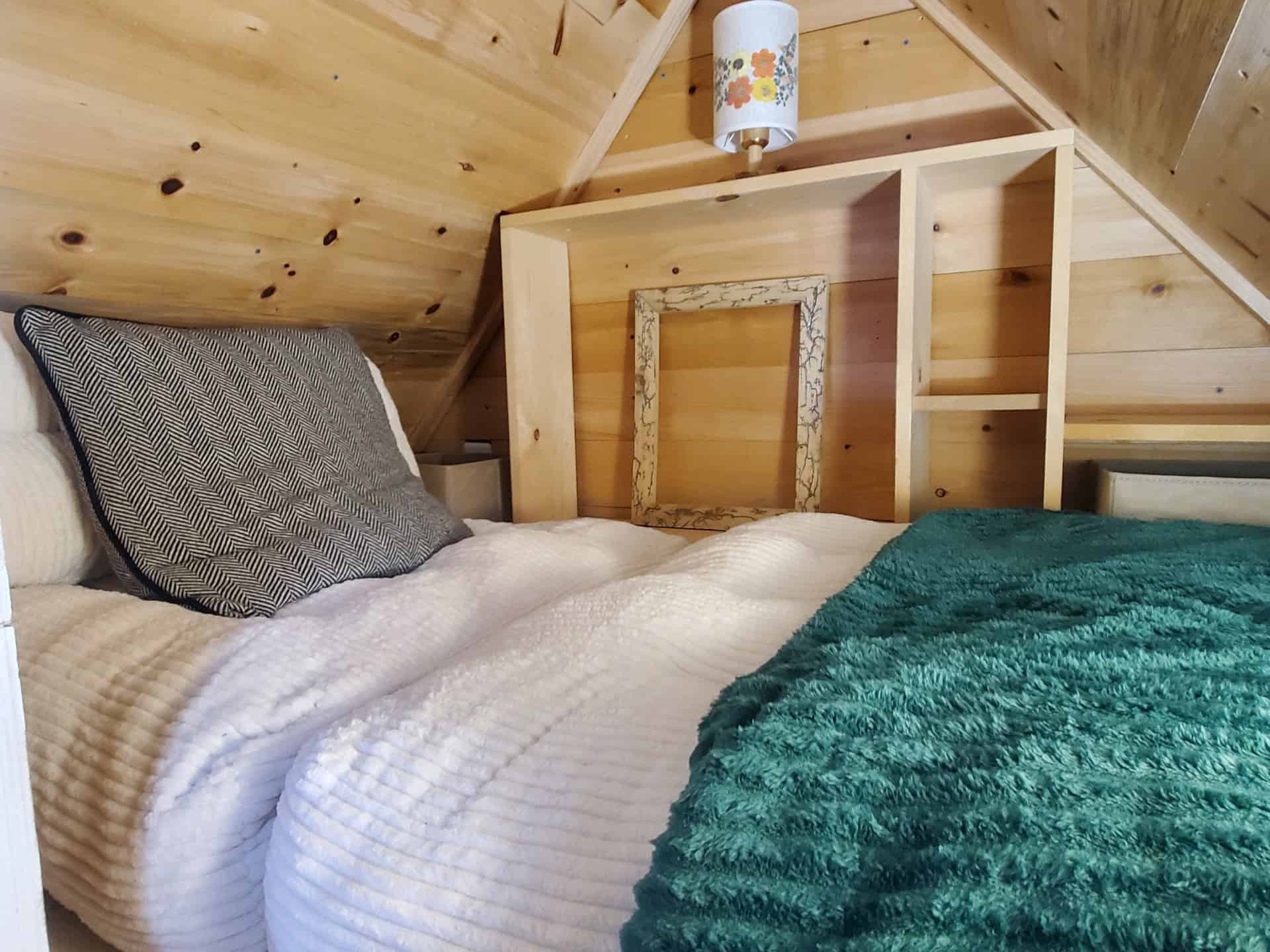 Second sleeping loft above the entry with built-in shelving unit and pendant lamp