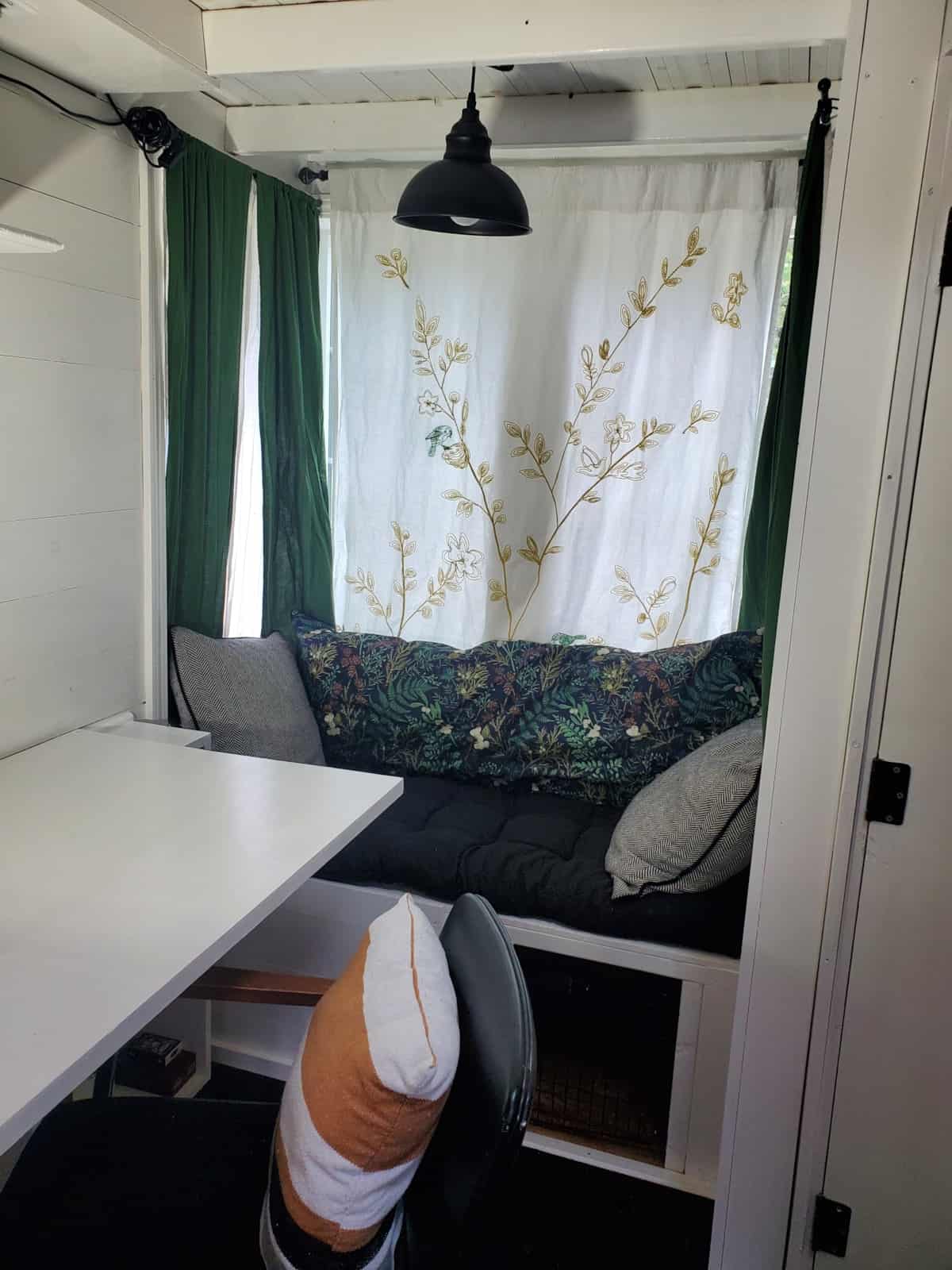 Window seat with cushions, pendant light and built-in desk in the great room of the Fencl tiny house