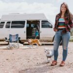Woman with dogs near her tiny house van during road trip adventure.